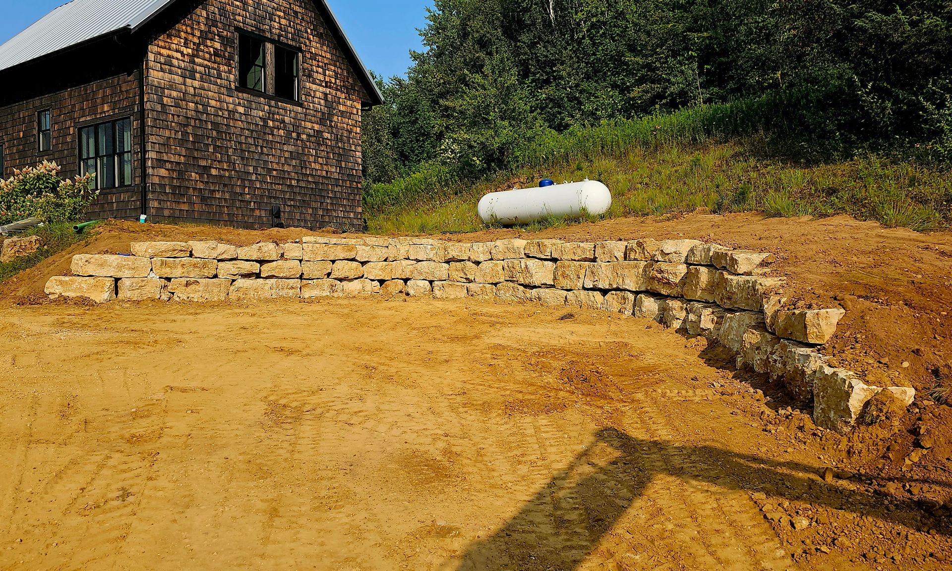 A brick building is sitting on top of a dirt hill next to a propane tank.