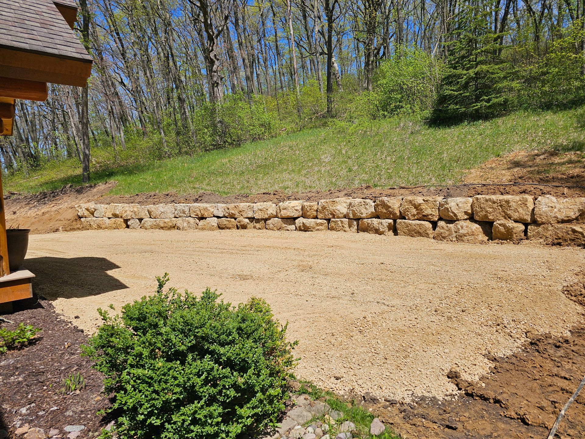 A stone wall is being built in the backyard of a house.