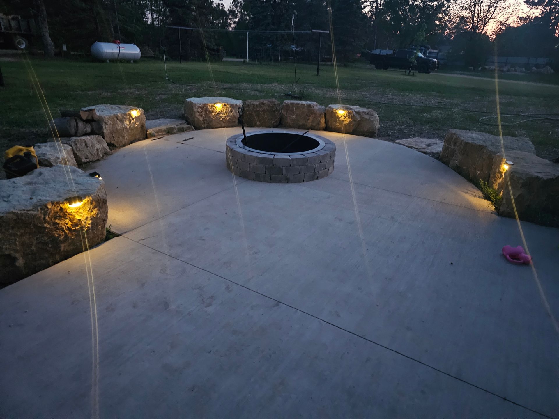 A fire pit is surrounded by rocks and is lit up at night.