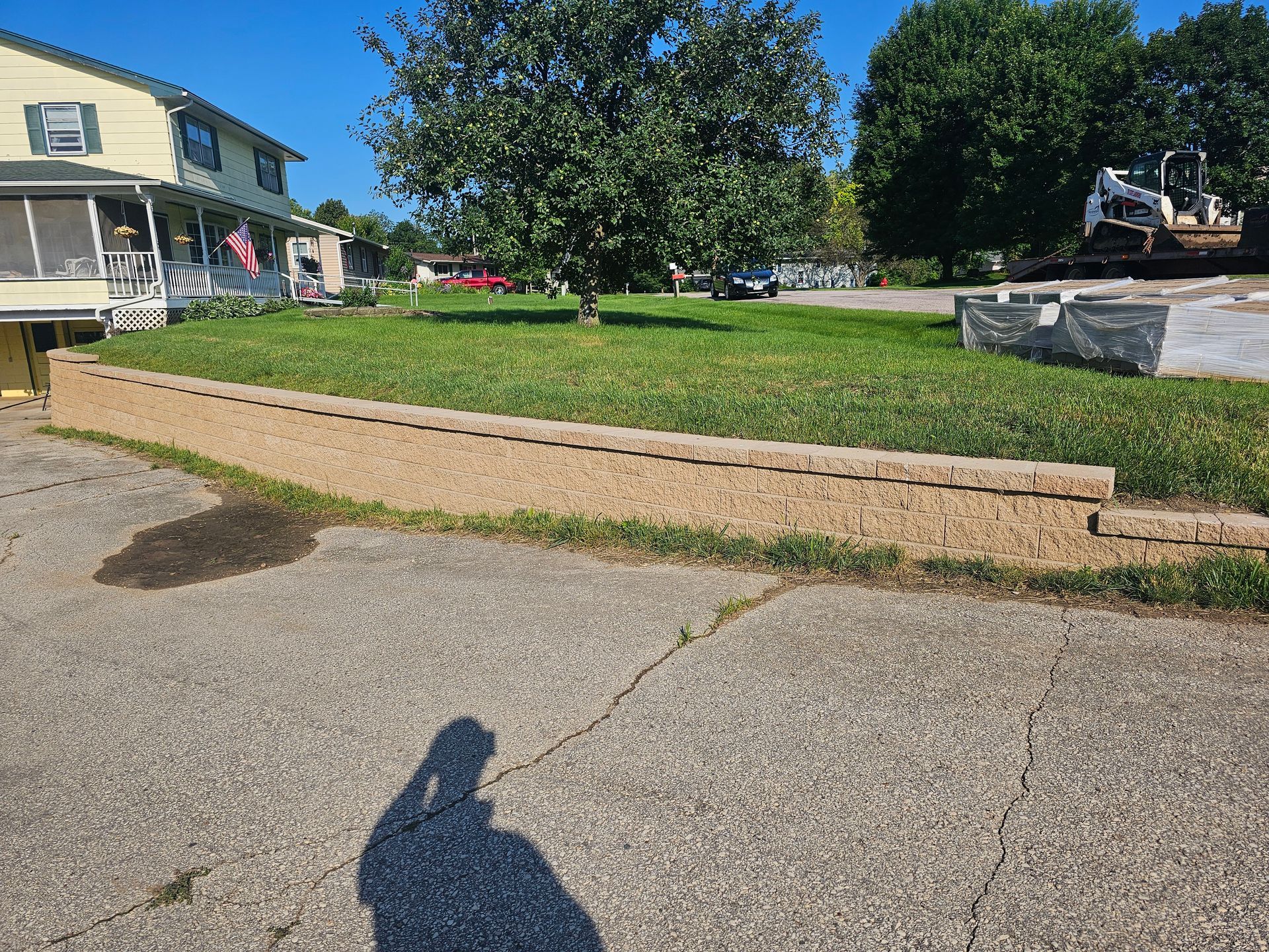 A shadow of a person is cast on the sidewalk in front of a house.
