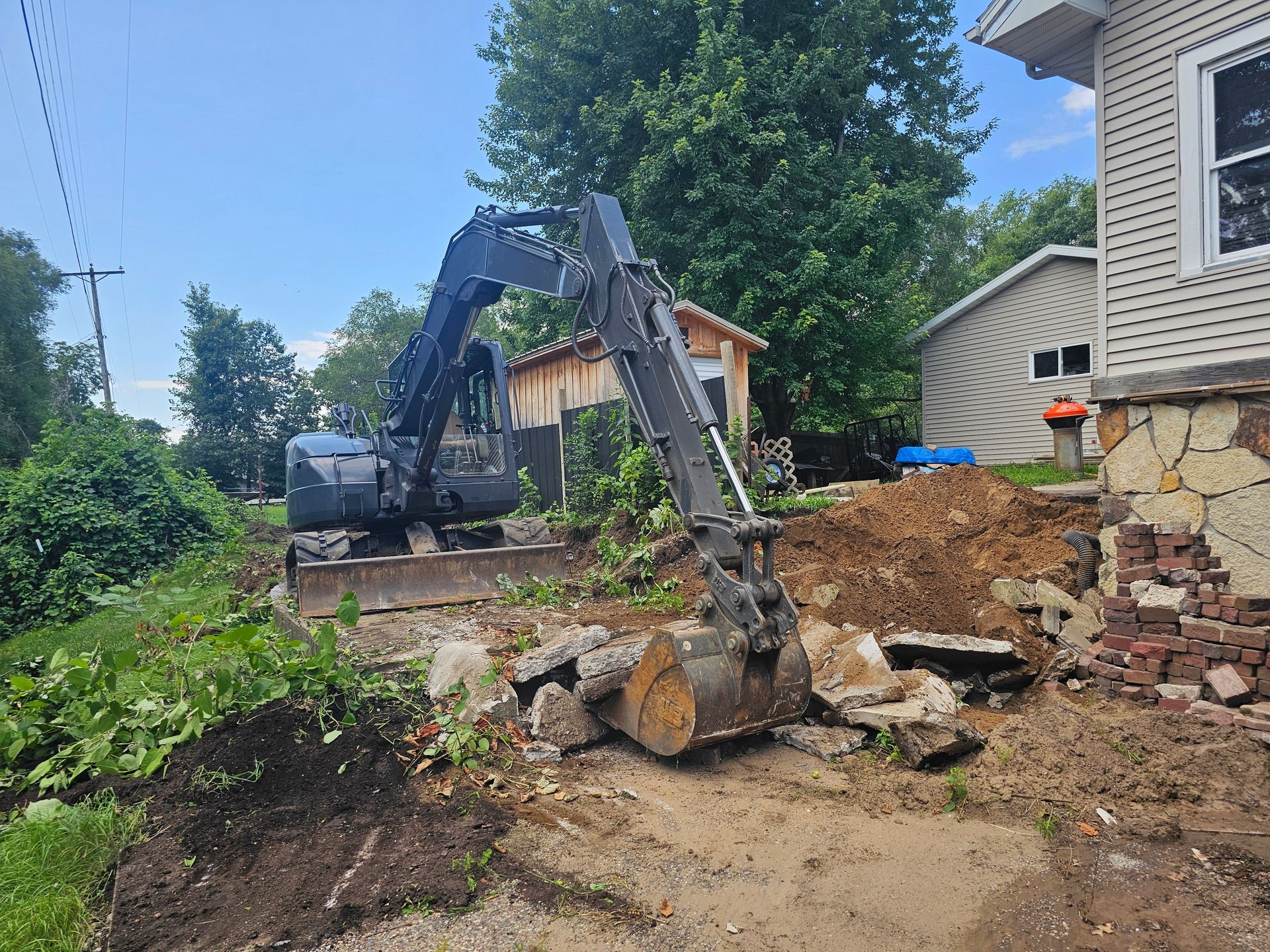 A large excavator is sitting in front of a house.