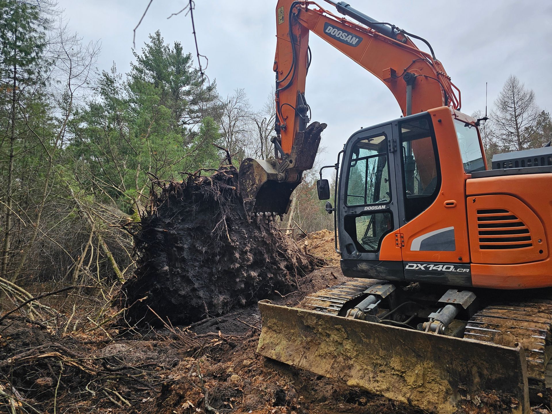 A bulldozer is digging a large pile of dirt in the woods.