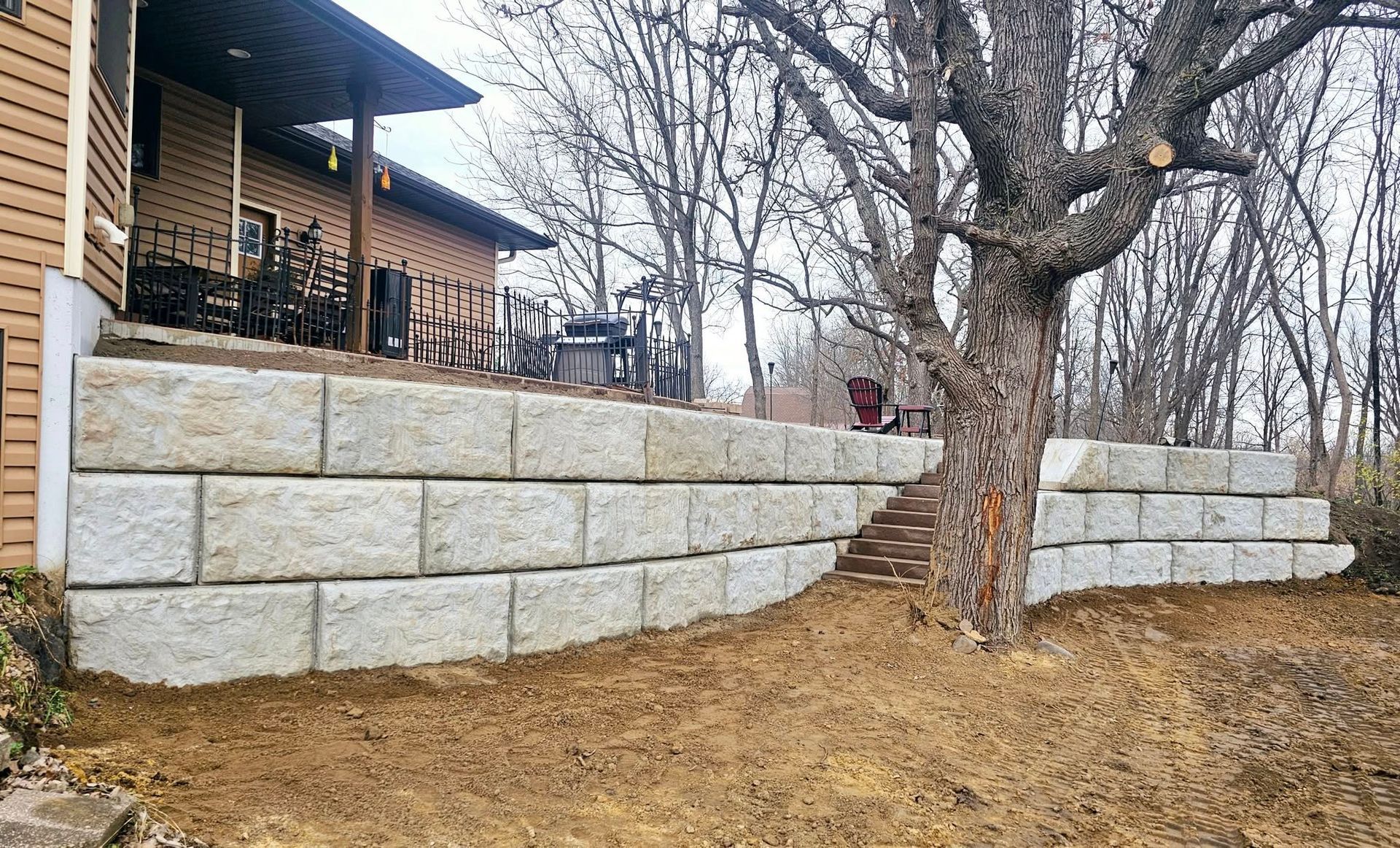 There is a large stone wall in the backyard of a house.