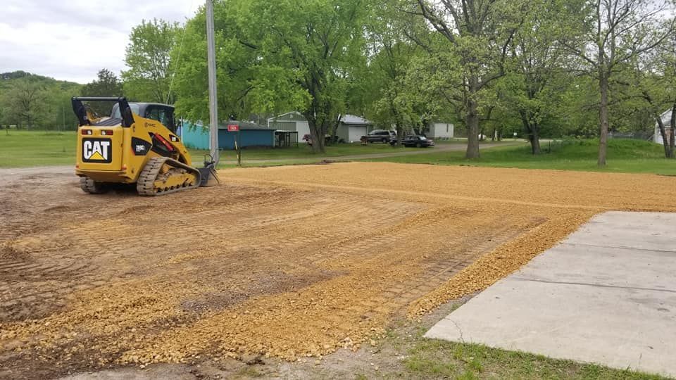 A yellow cat bulldozer is moving dirt in a parking lot.