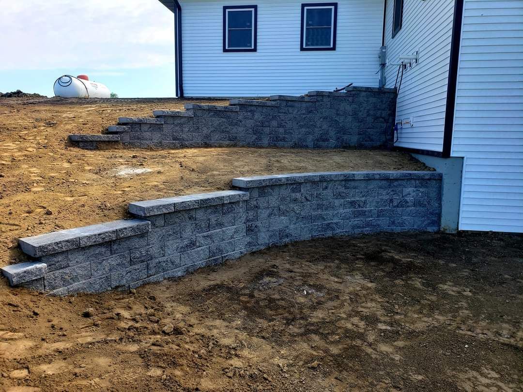 A stone wall is being built in front of a house.