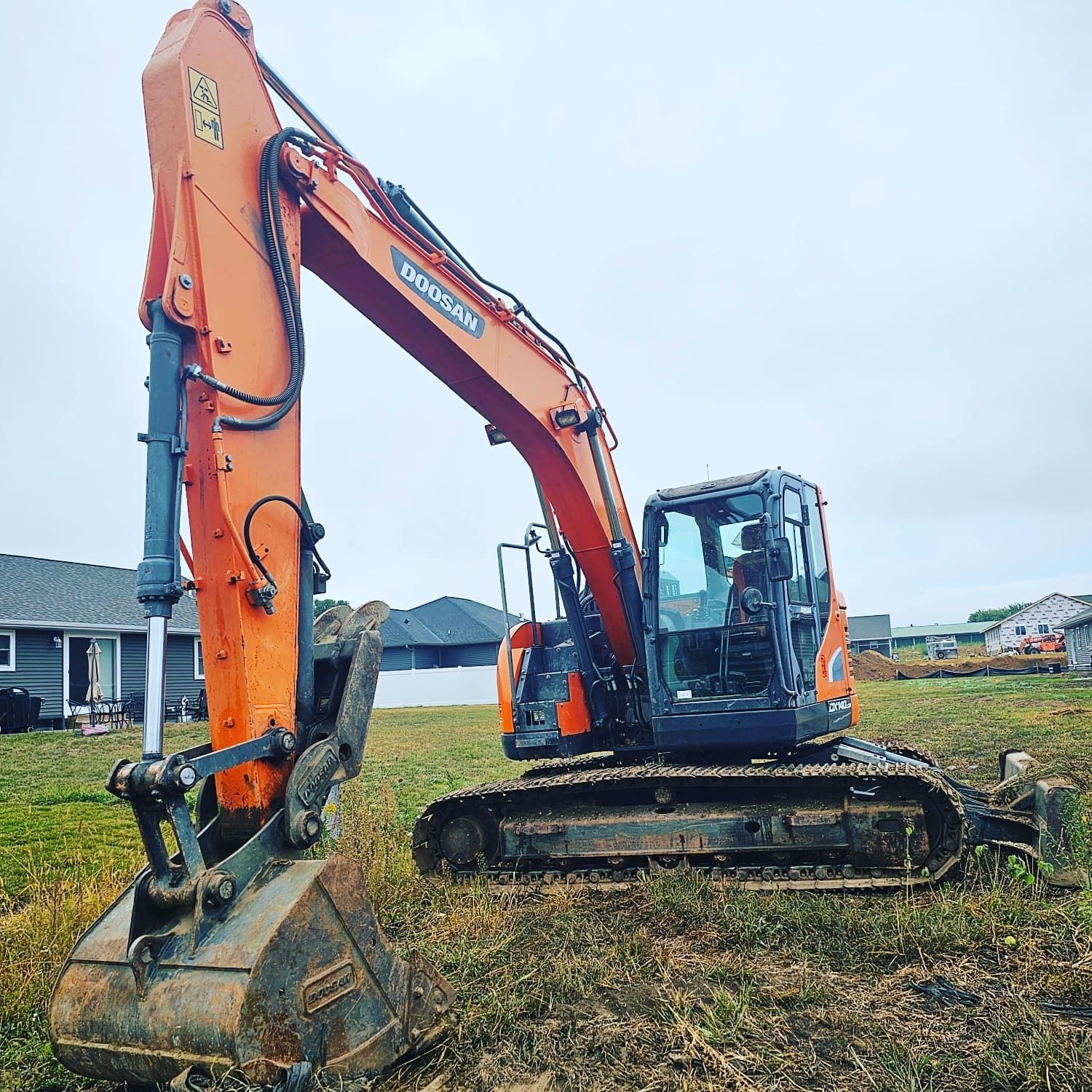 A large orange excavator is sitting in the middle of a field.