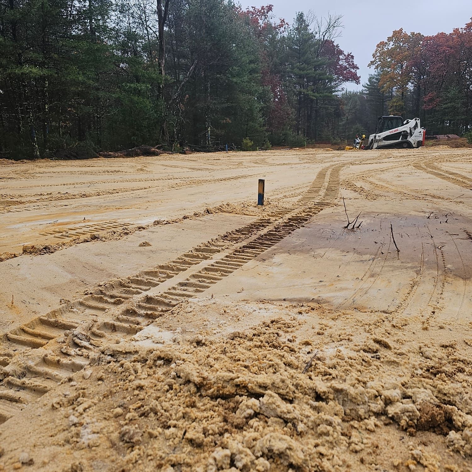 A truck is driving down a dirt road with trees in the background