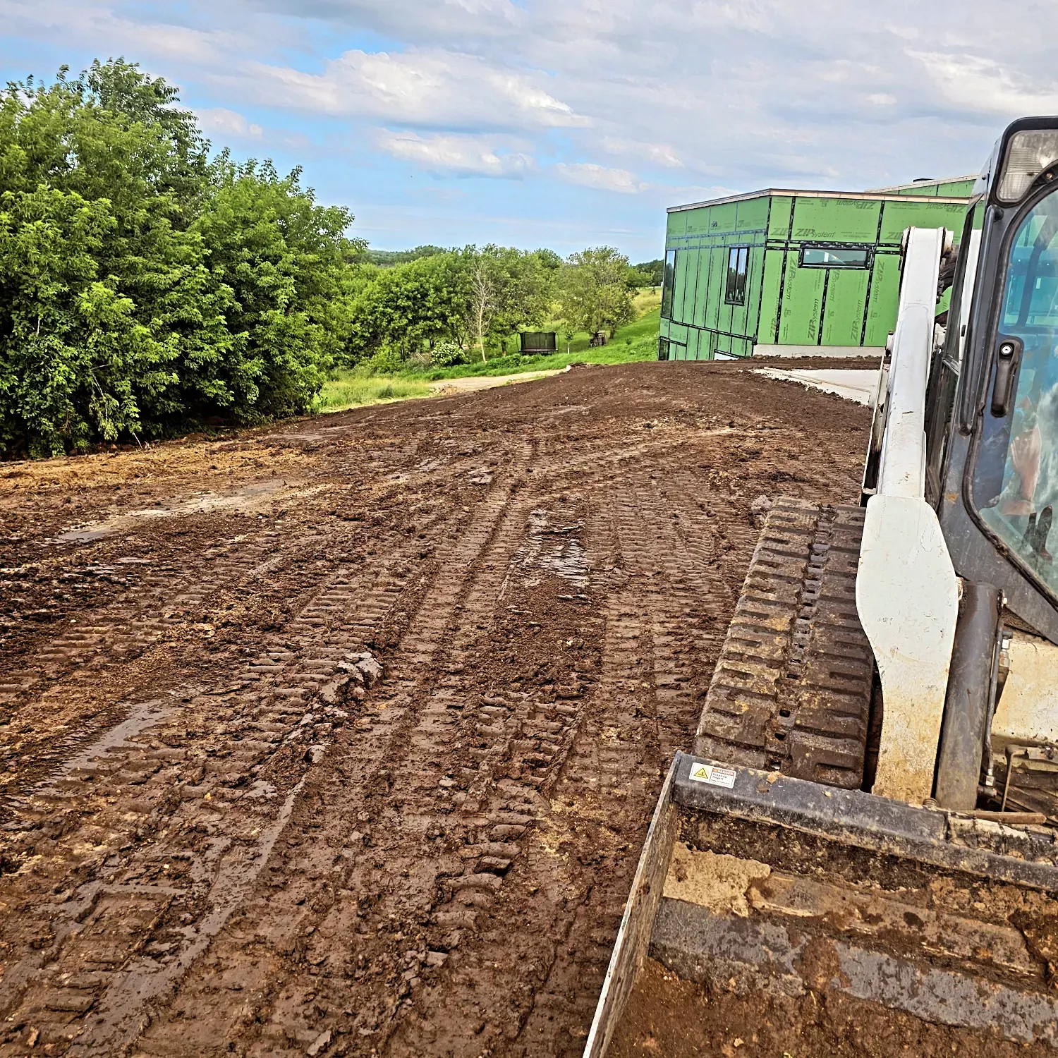 A bulldozer is moving dirt on a muddy road.