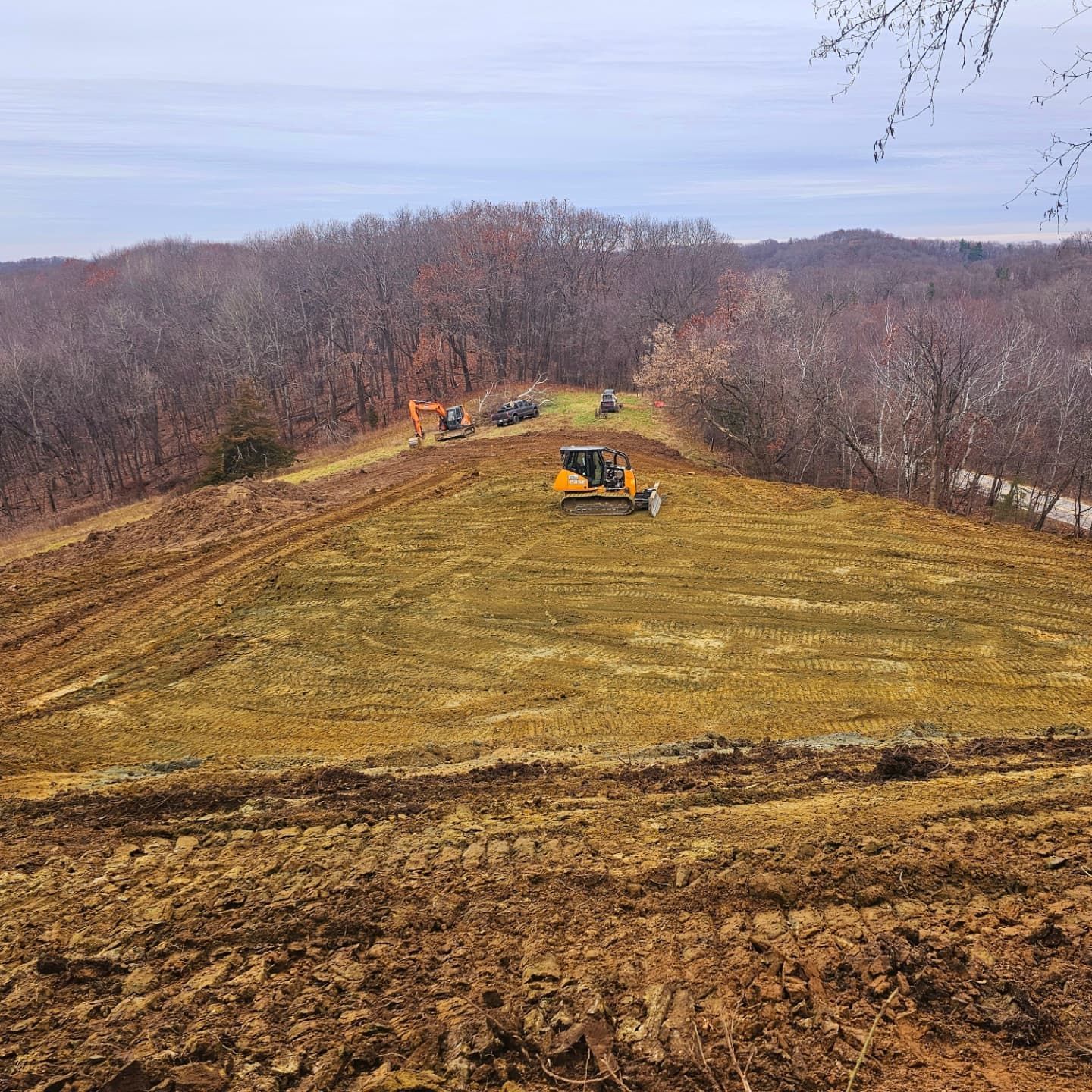 A large field with a lot of dirt and trees in the background.