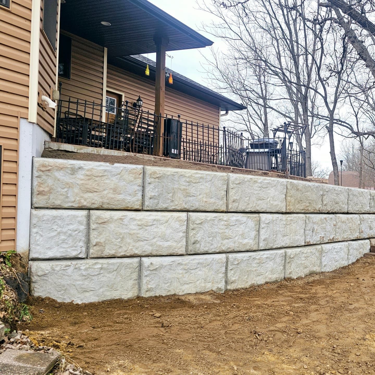 A large stone wall is in front of a house.