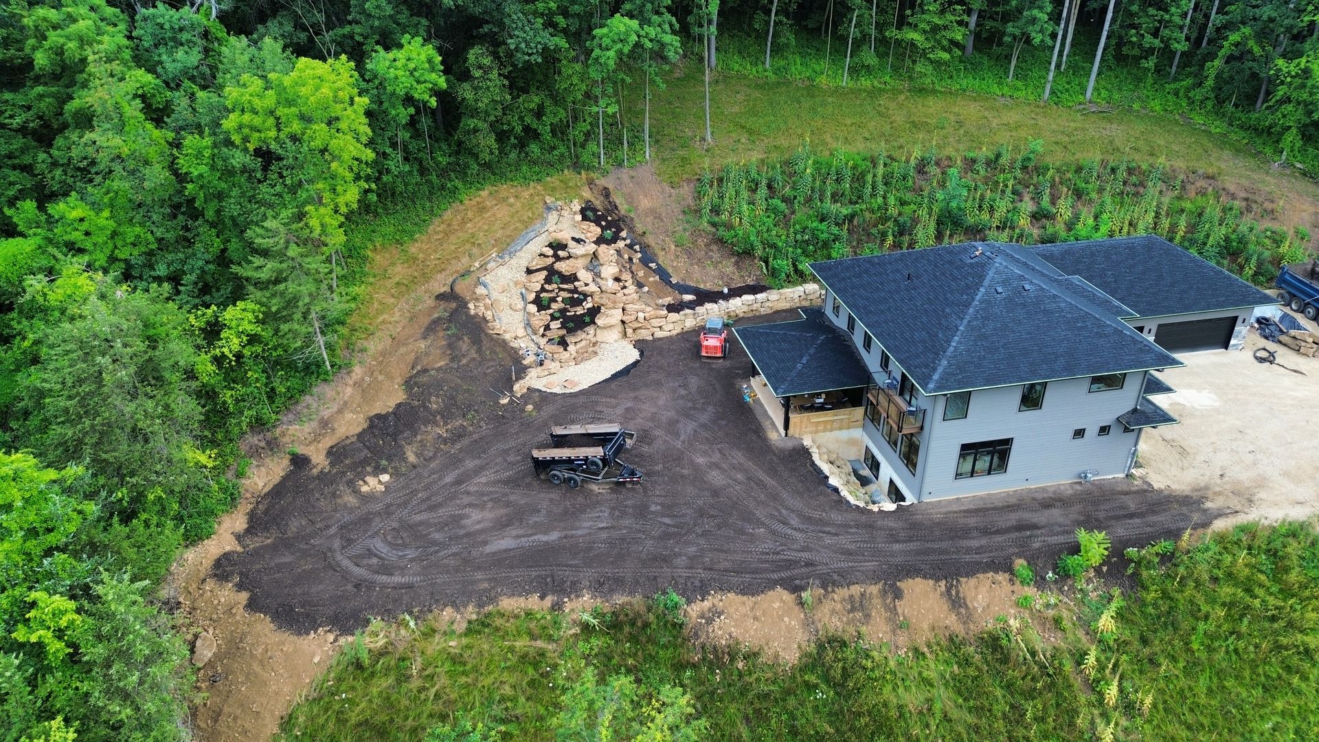 An aerial view of a house under construction in the middle of a forest.