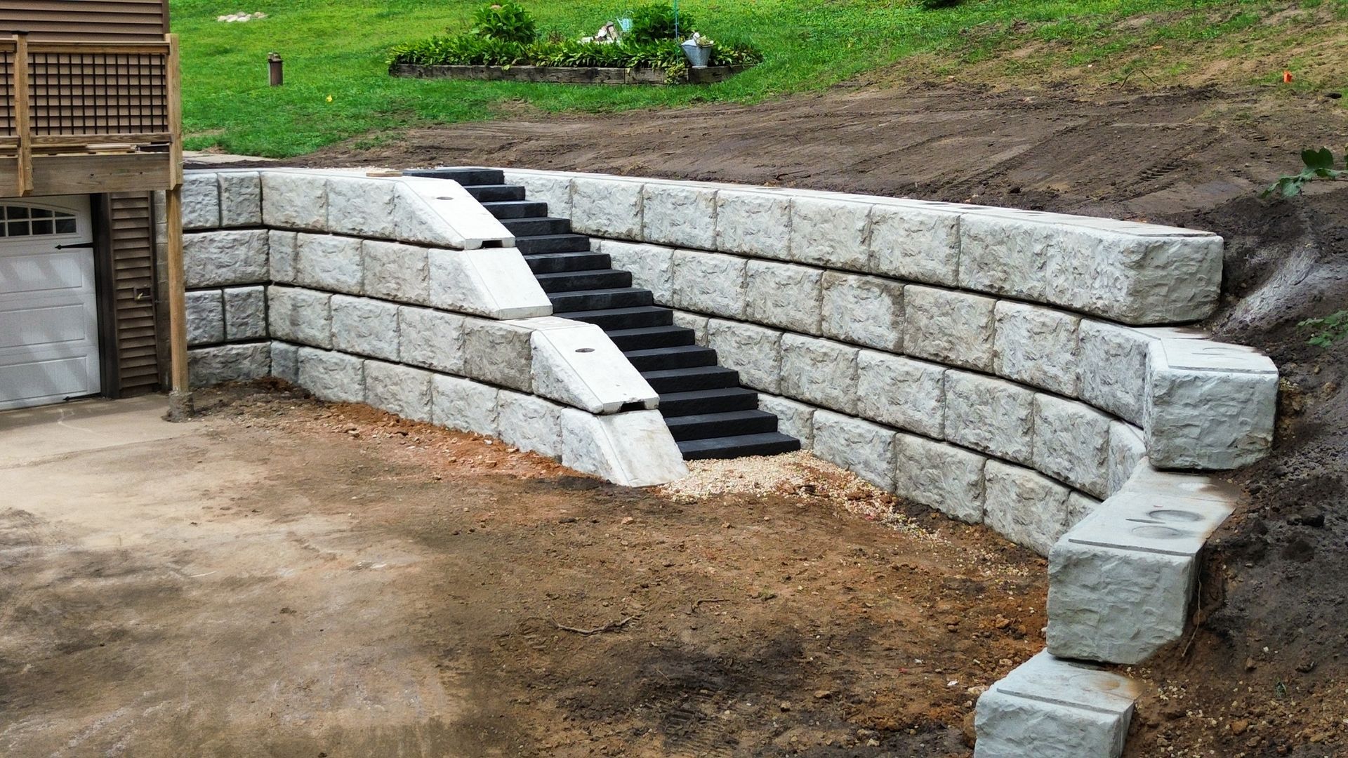 A stone wall with stairs leading up to a garage.