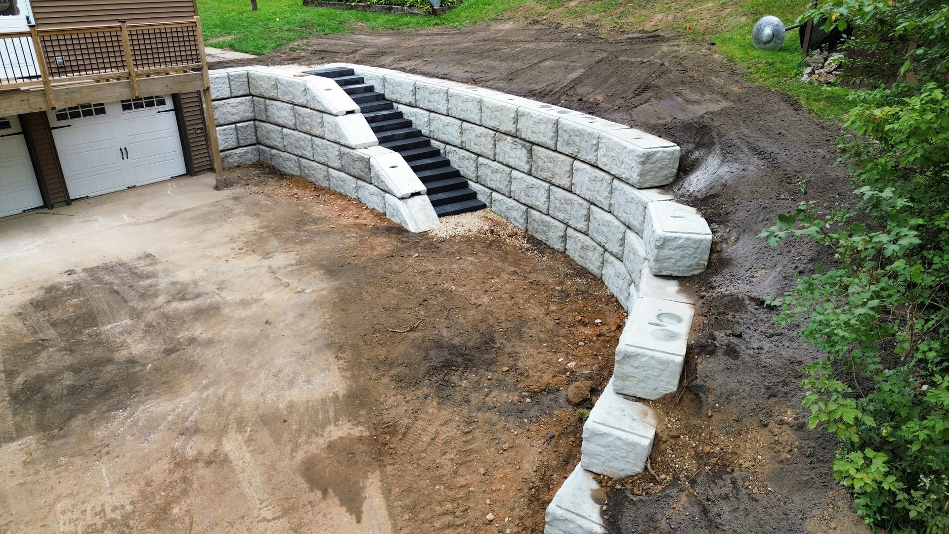 A stone wall with stairs leading up to it is being built in front of a house.