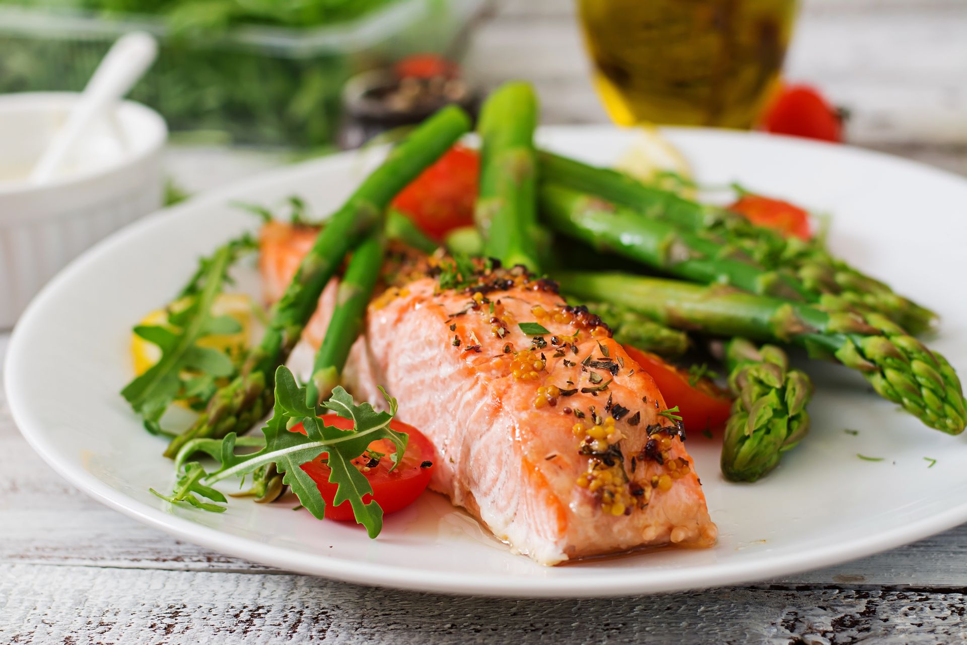 A white plate topped with salmon , asparagus and tomatoes.