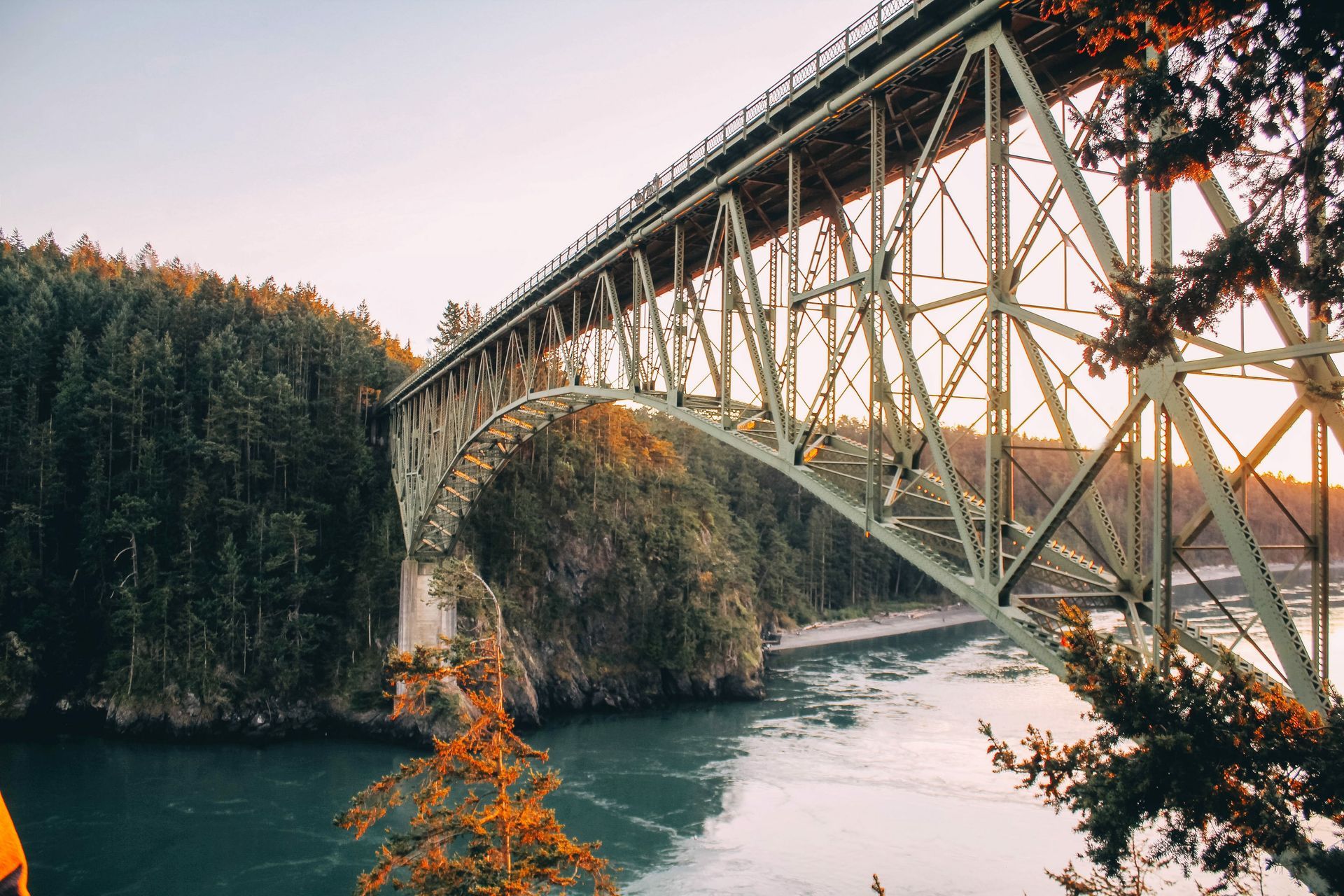 A bridge over a river surrounded by trees and a body of water.