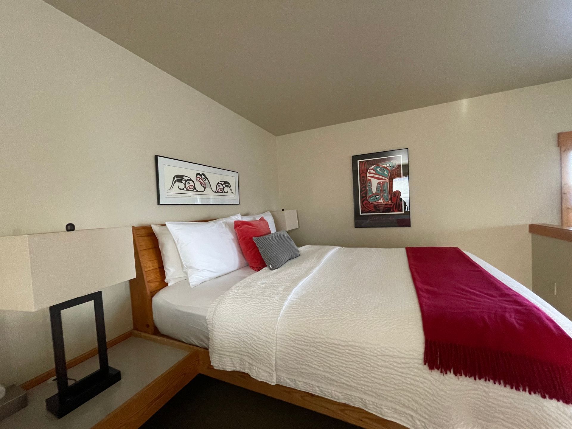 A bedroom with a bed , two lamps and a picture on the wall.