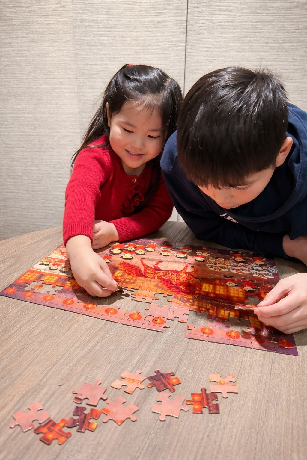 two young asian children enjoying putting a colorful lunar new year puzzle together