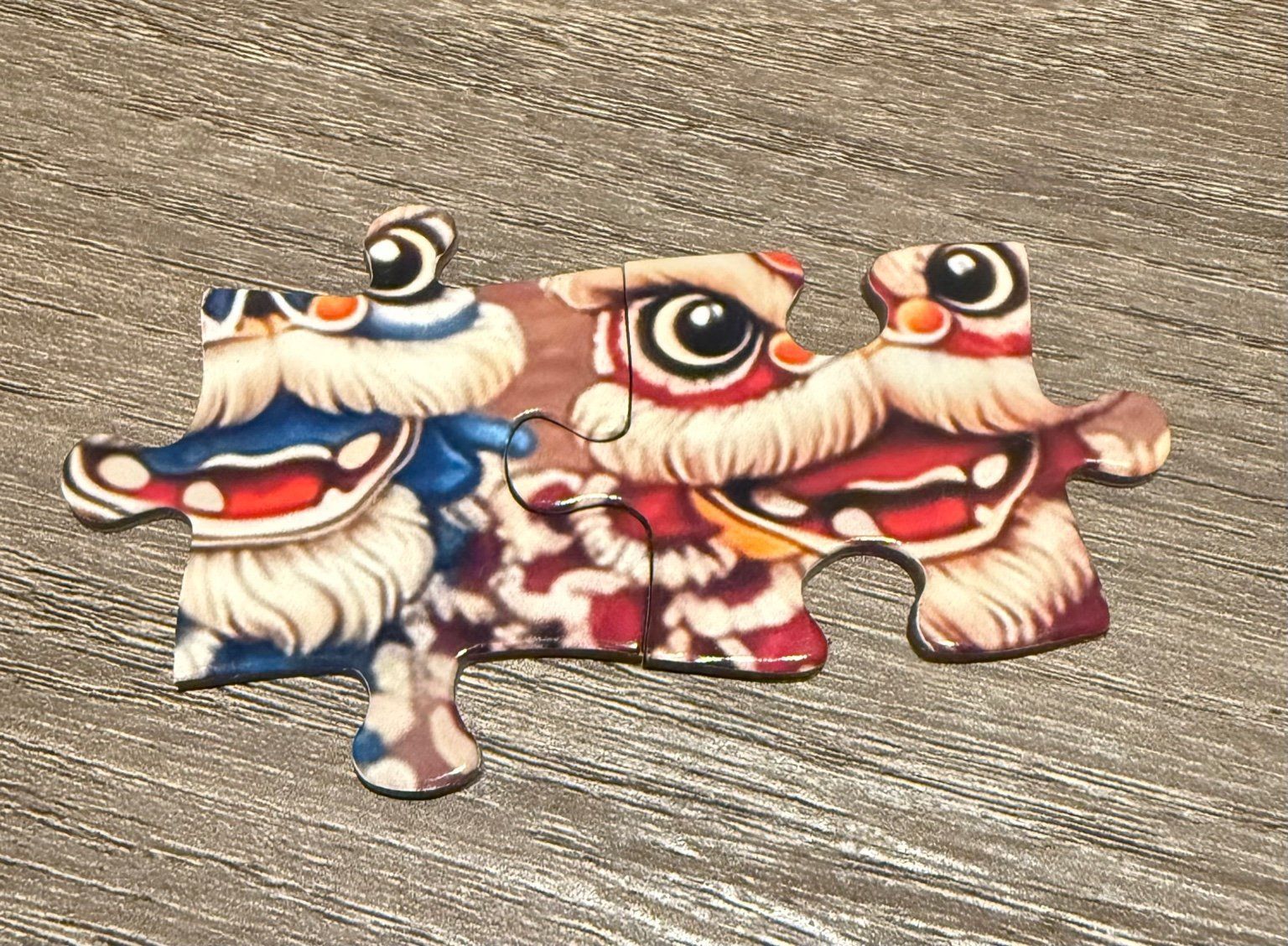 two puzzle pieces pieced together, showing lion dancer faces