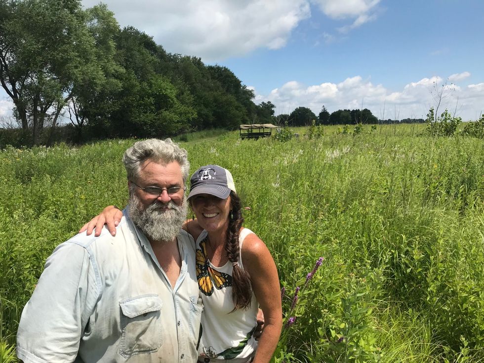 A man and a woman are posing for a picture in a field.