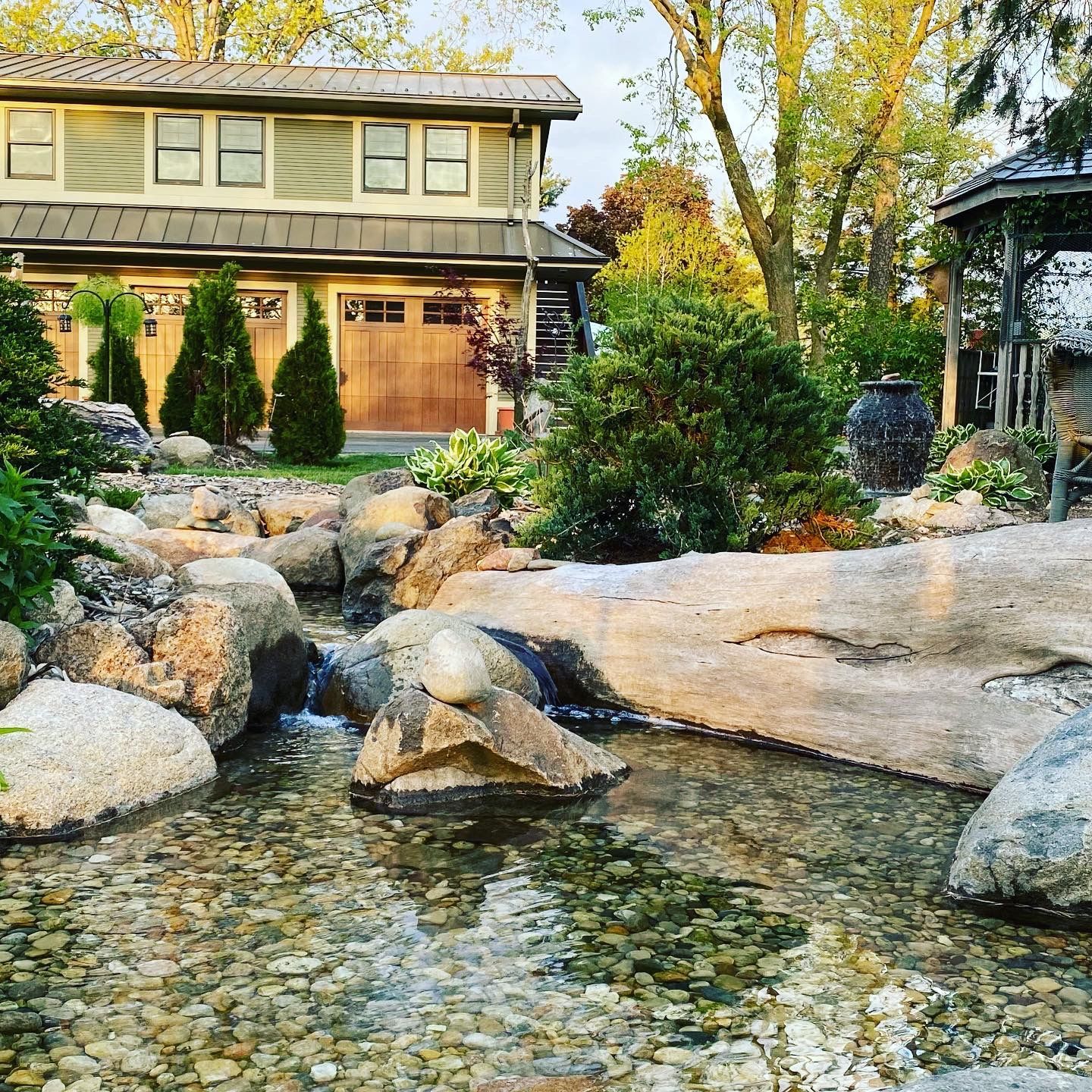 A house with a wooden garage door and a pond in front of it