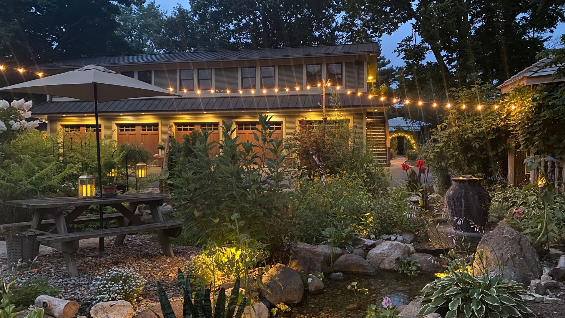 A house with a picnic table and umbrella in front of it at night.