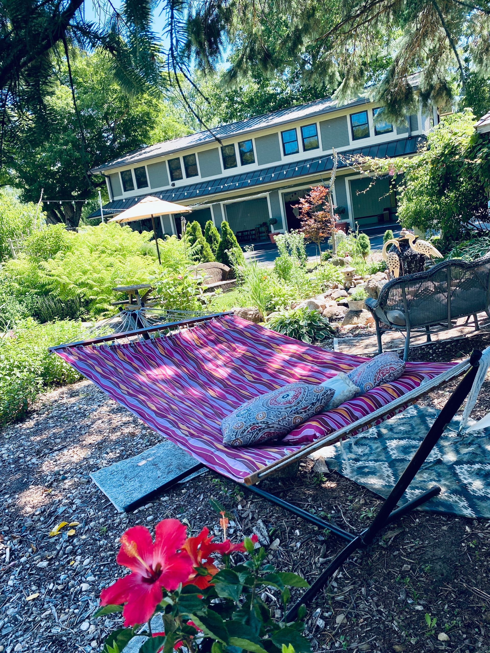 A hammock is sitting in the dirt in front of a house.