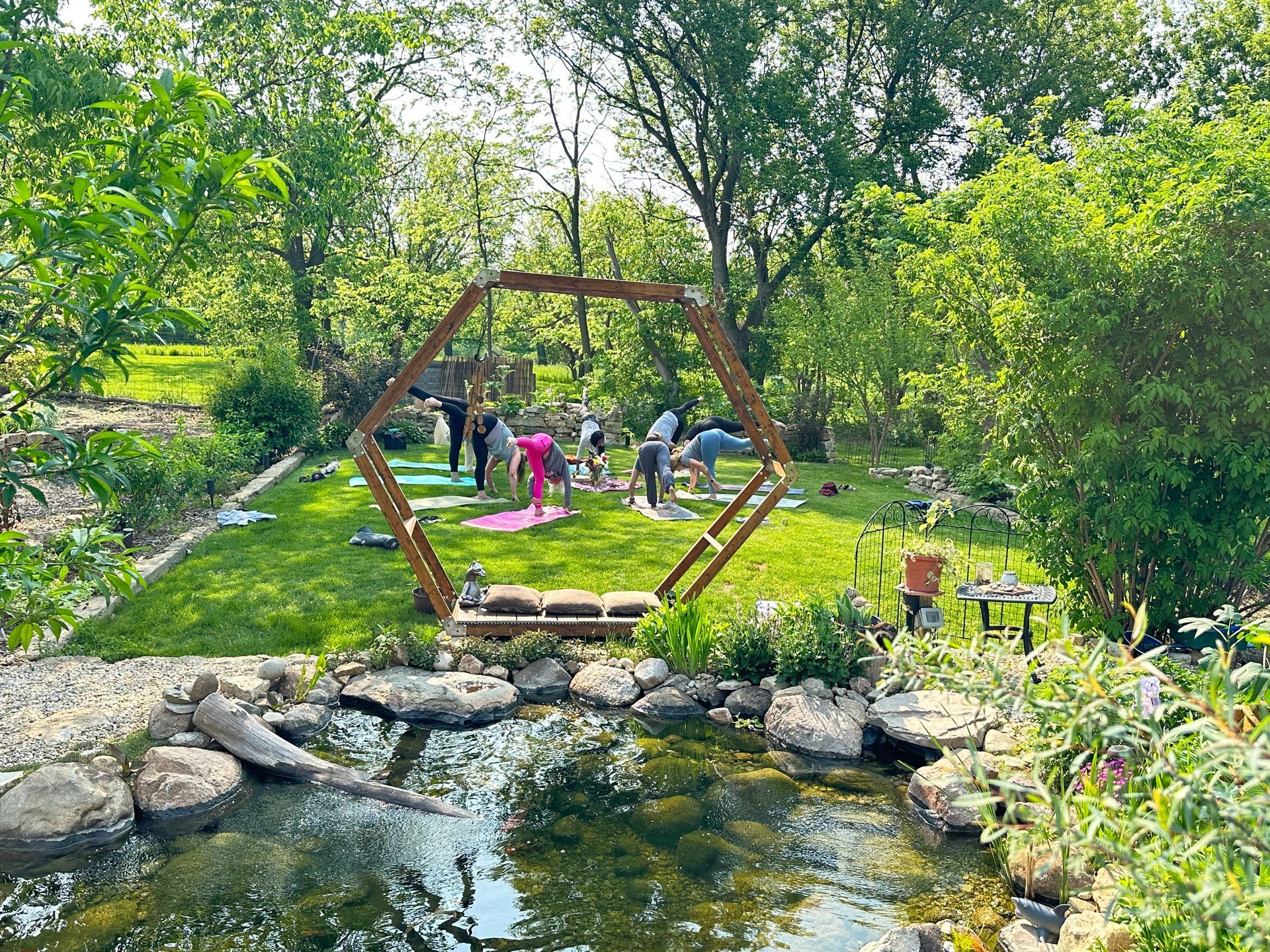 A group of people are doing yoga in a park next to a pond.