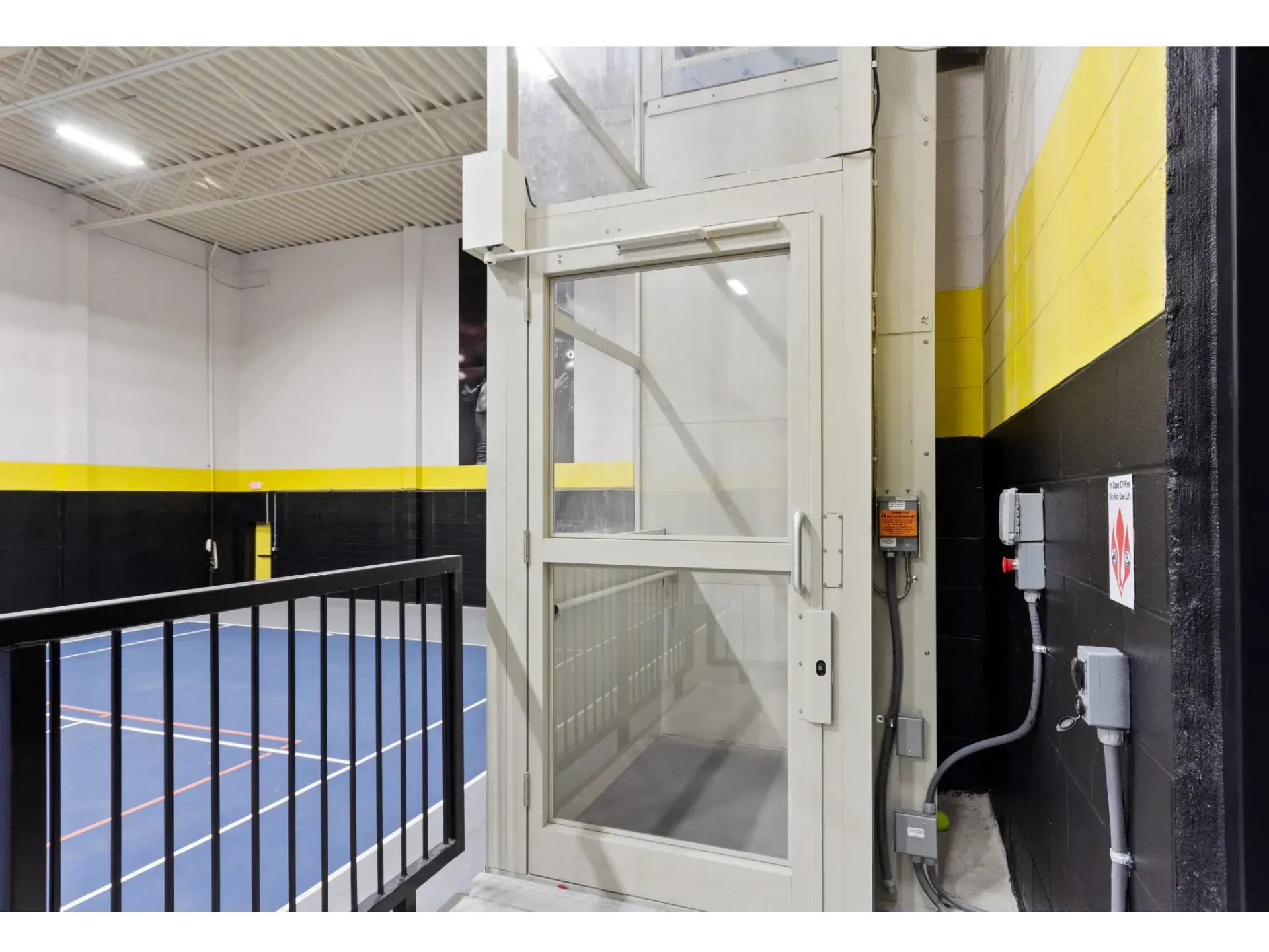 Interior view of an elevator with glass doors in a sports facility