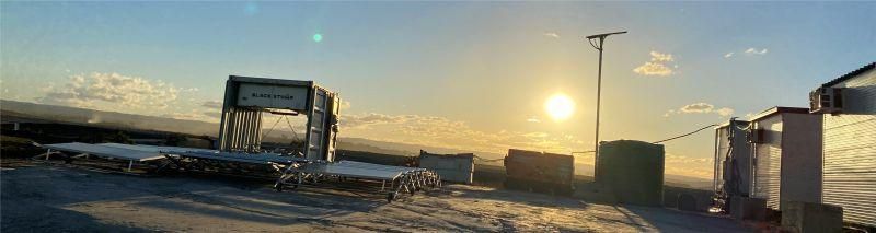Scenic sunrise over a body of water, with buildings and a sign structure in the foreground.