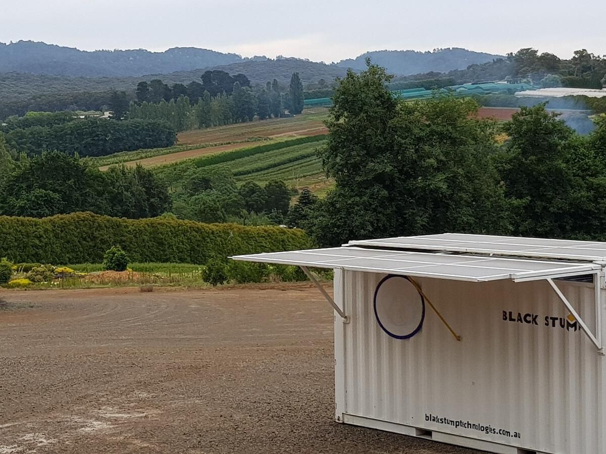 White food kiosk with open awning, overlooking a green valley and distant hills.