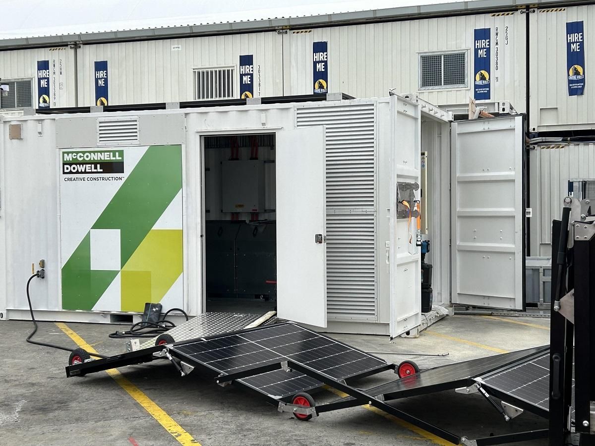 Solar panels on a wheeled platform extend from a white container with an open door.