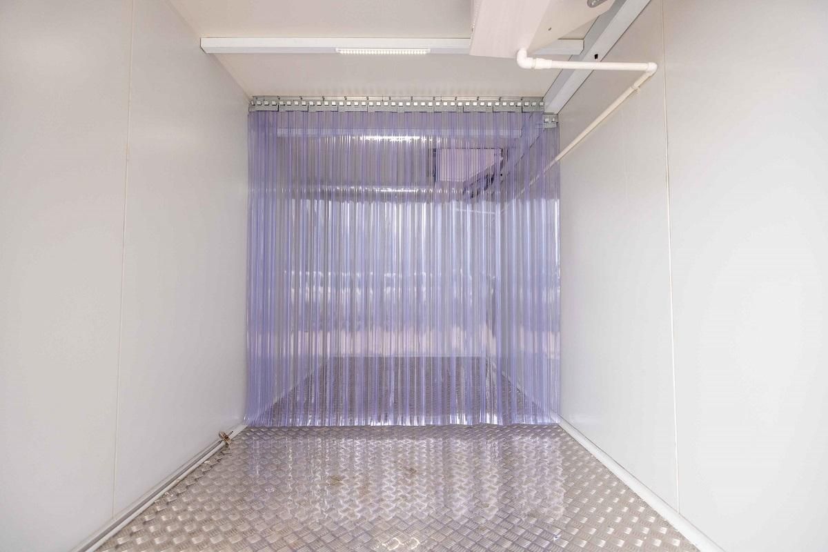 Interior of a white room with a clear plastic strip curtain in the doorway.
