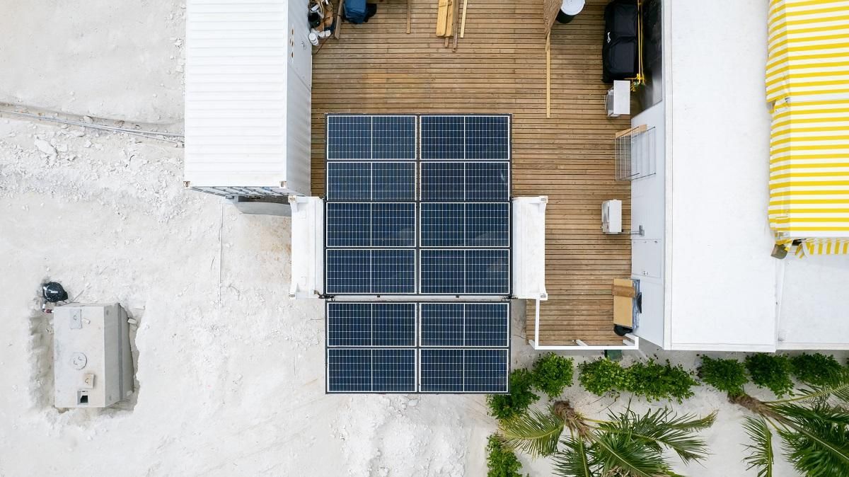 Overhead view of solar panels on a wooden deck next to a white building.