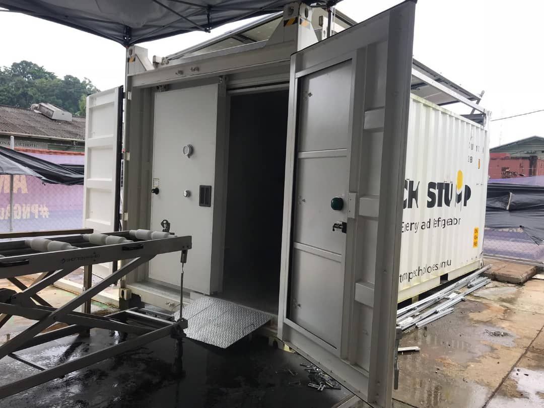 Shipping container with open doors; ramp at the entrance. White container with black and yellow text.