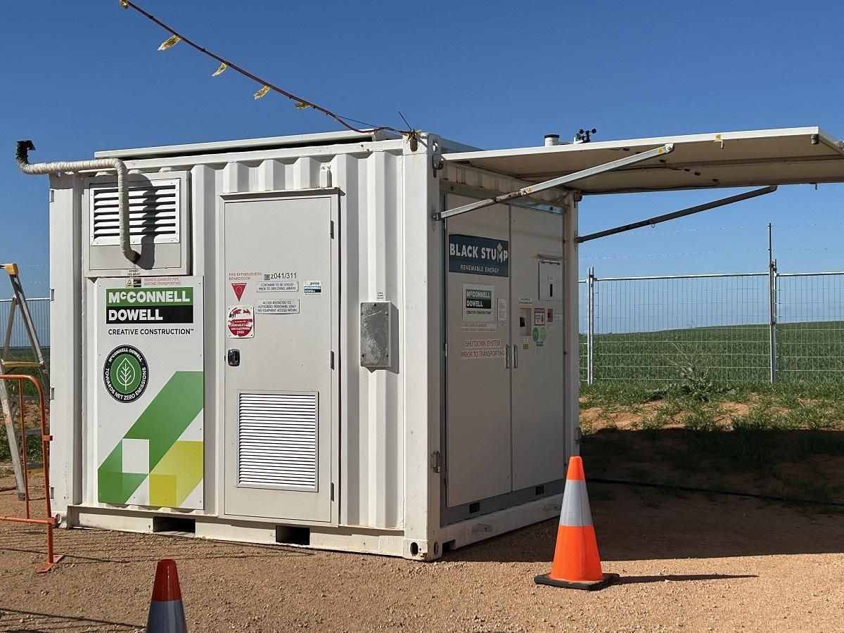 White container with open awning, markings, and a traffic cone, outdoors.