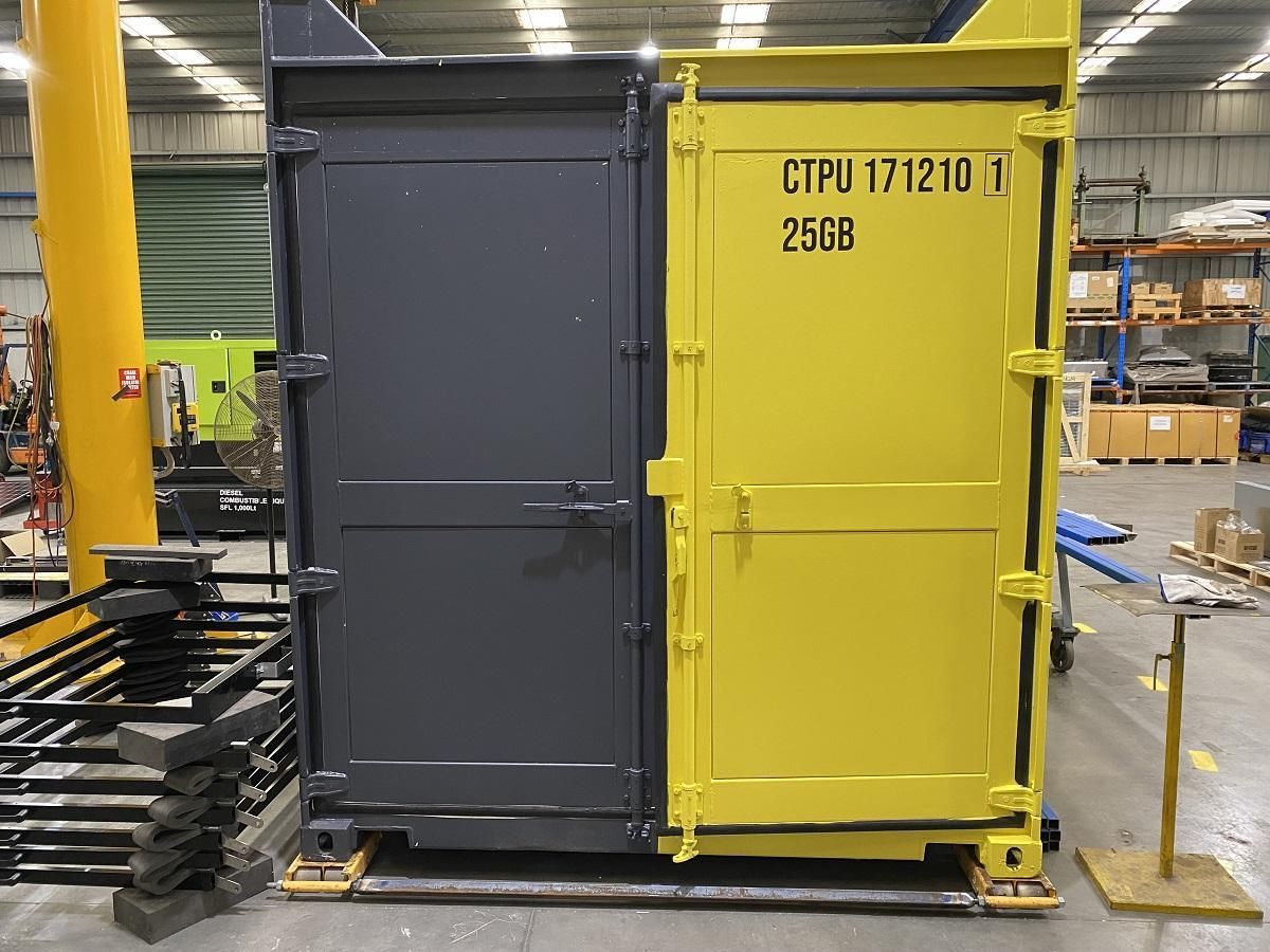 Two shipping containers, one gray and one yellow, side by side in a warehouse.