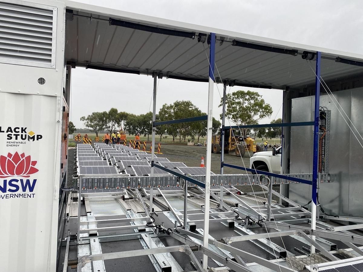 Mobile solar panel cleaning station with panels and support structures. NSW government branding on the side.