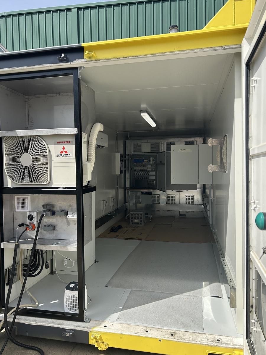 Interior of a container unit, possibly a lab, with equipment and a climate control unit visible.