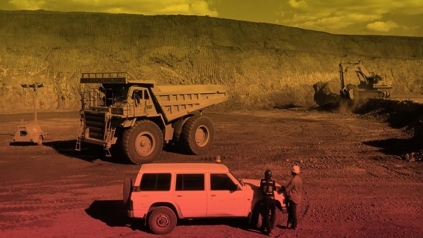 Large dump truck, SUV, and construction workers in an open-pit mine.