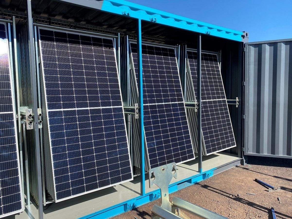 Solar panels in a shipping container, tilted outward, blue and gray, set outdoors.
