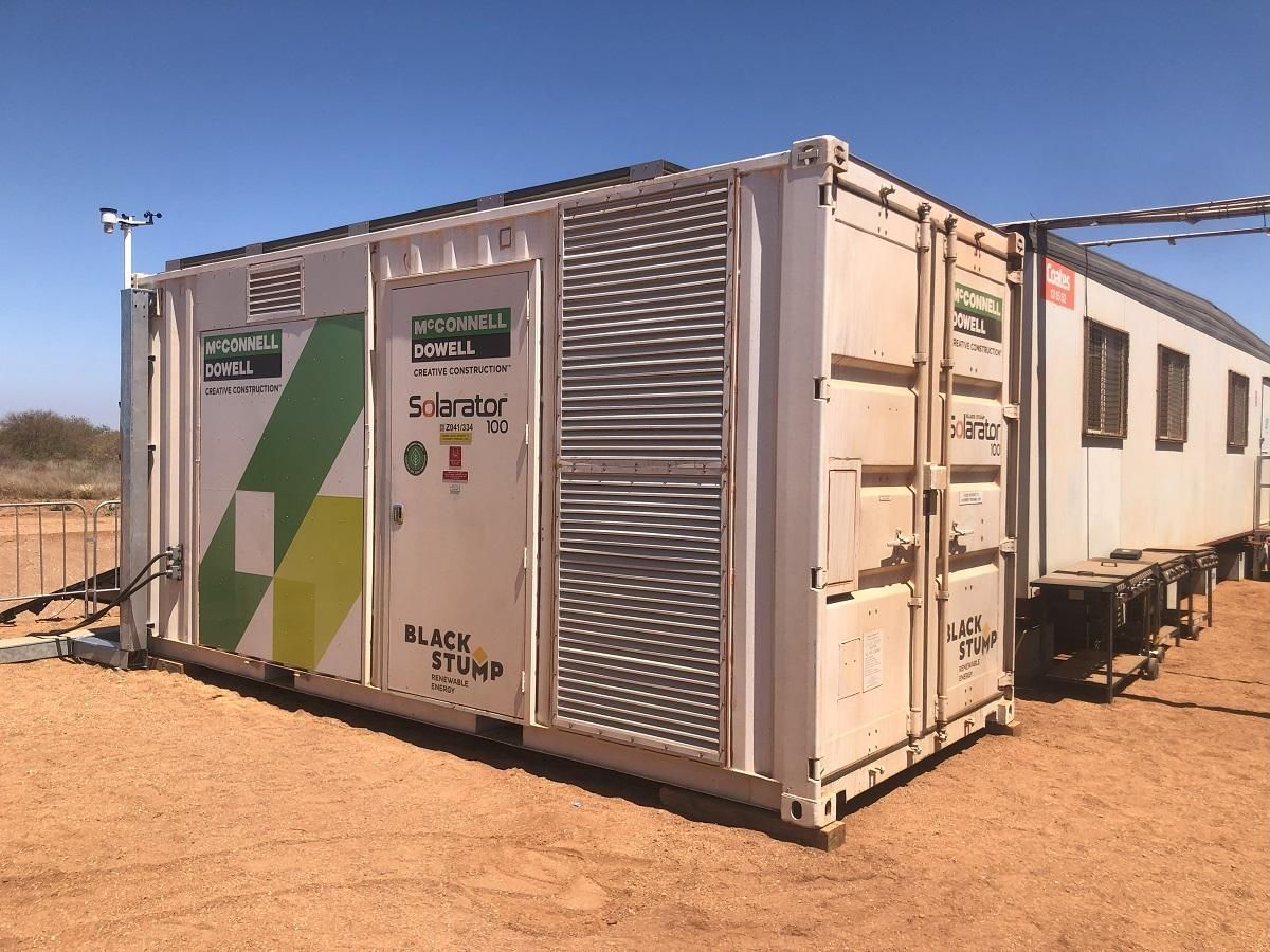 White industrial container, with branding, in a desert setting, connected to a trailer with windows.