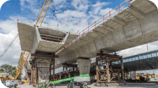 Construction site of a concrete overpass bridge, supported by columns and scaffolding.