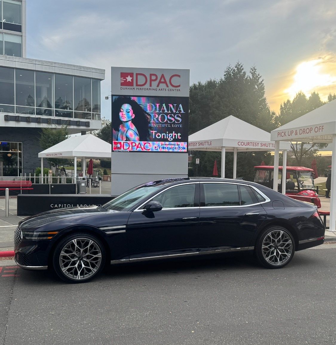 Concert stage at night with pyrotechnics, confetti, and crowd of people with arms raised.