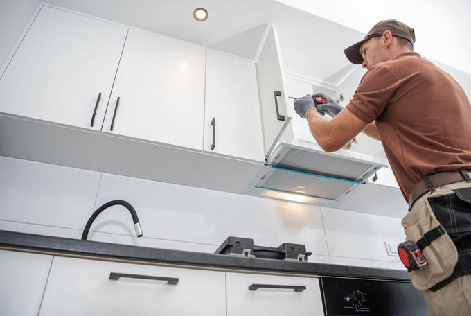 A man is installing a cabinet door in a kitchen.