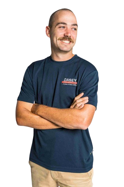 A man with a mustache is wearing a blue t-shirt and khaki pants.