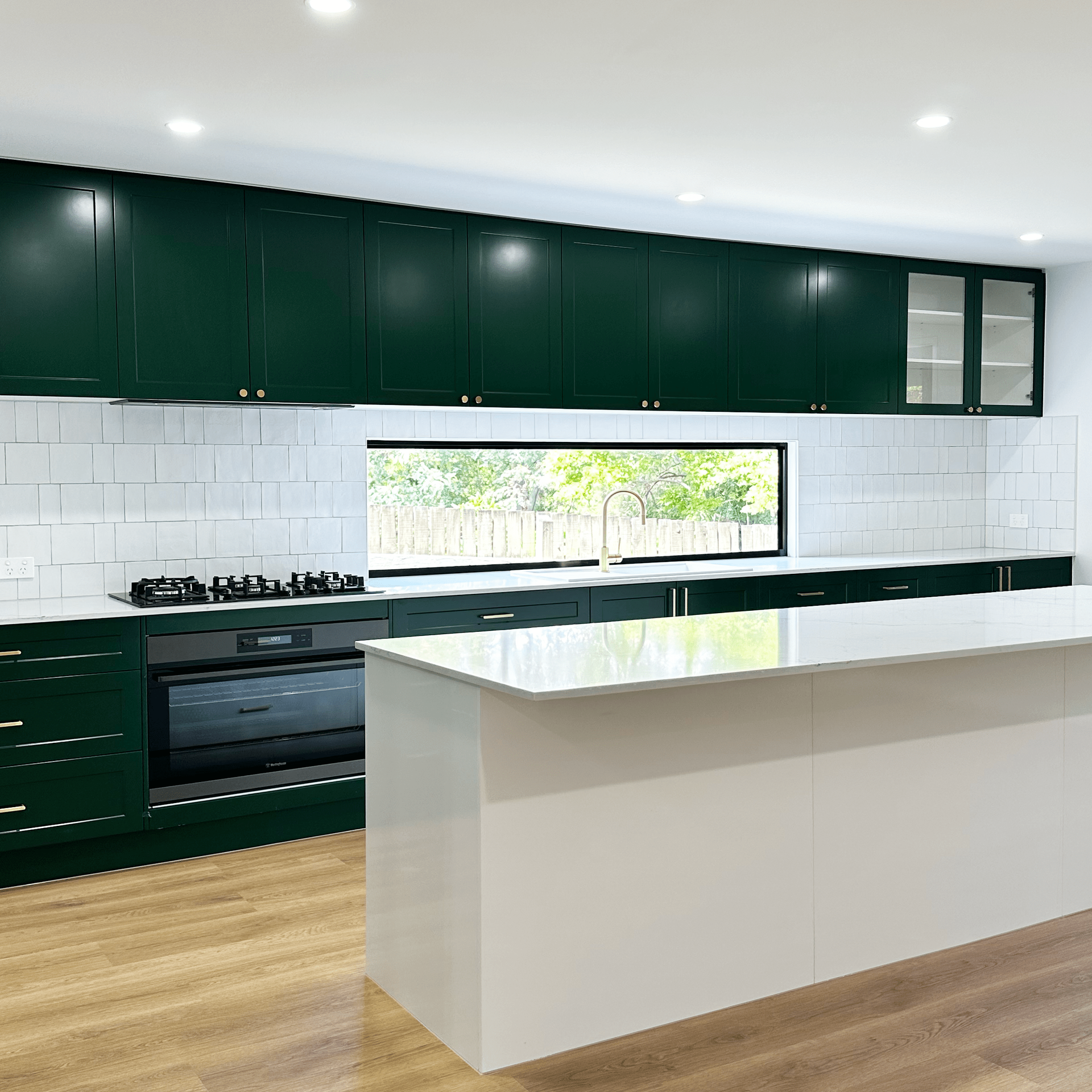 A kitchen with green cabinets and white counter tops