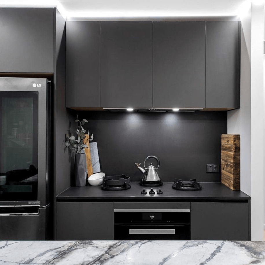 A kitchen with black cabinets and a marble counter top.