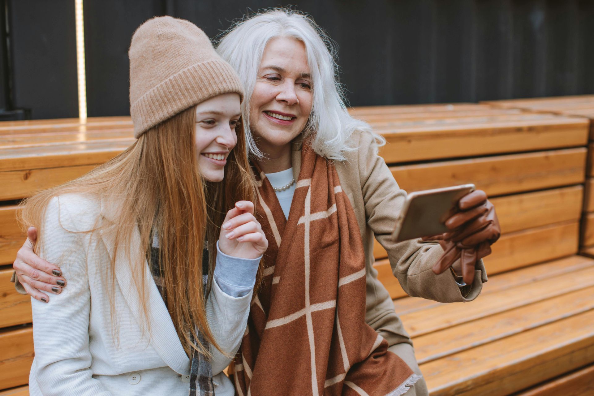 An older woman and a younger woman are taking a selfie with a cell phone.