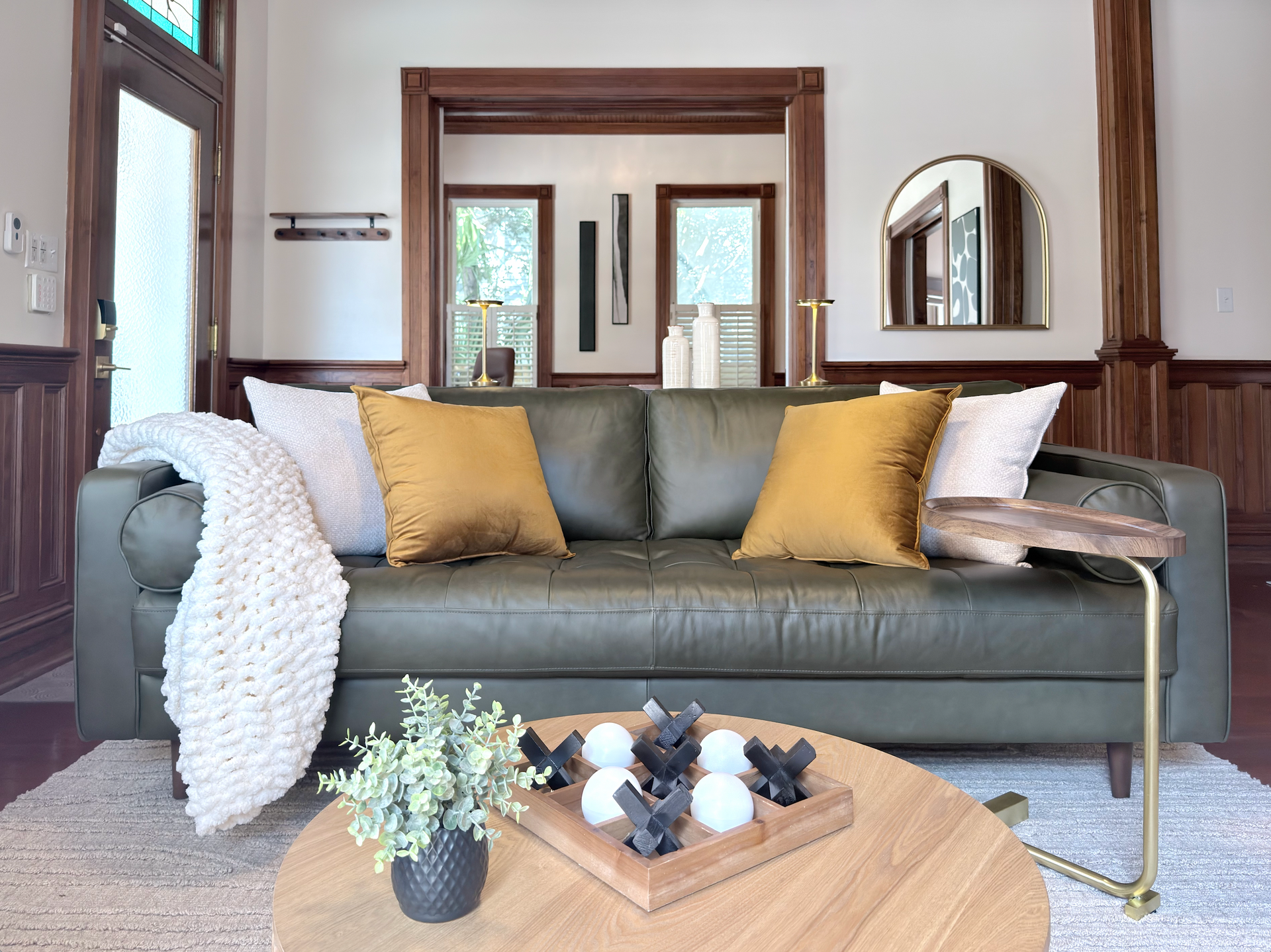 Modern living room with gray sofa, yellow pillows, wooden coffee table, and wall mirror.