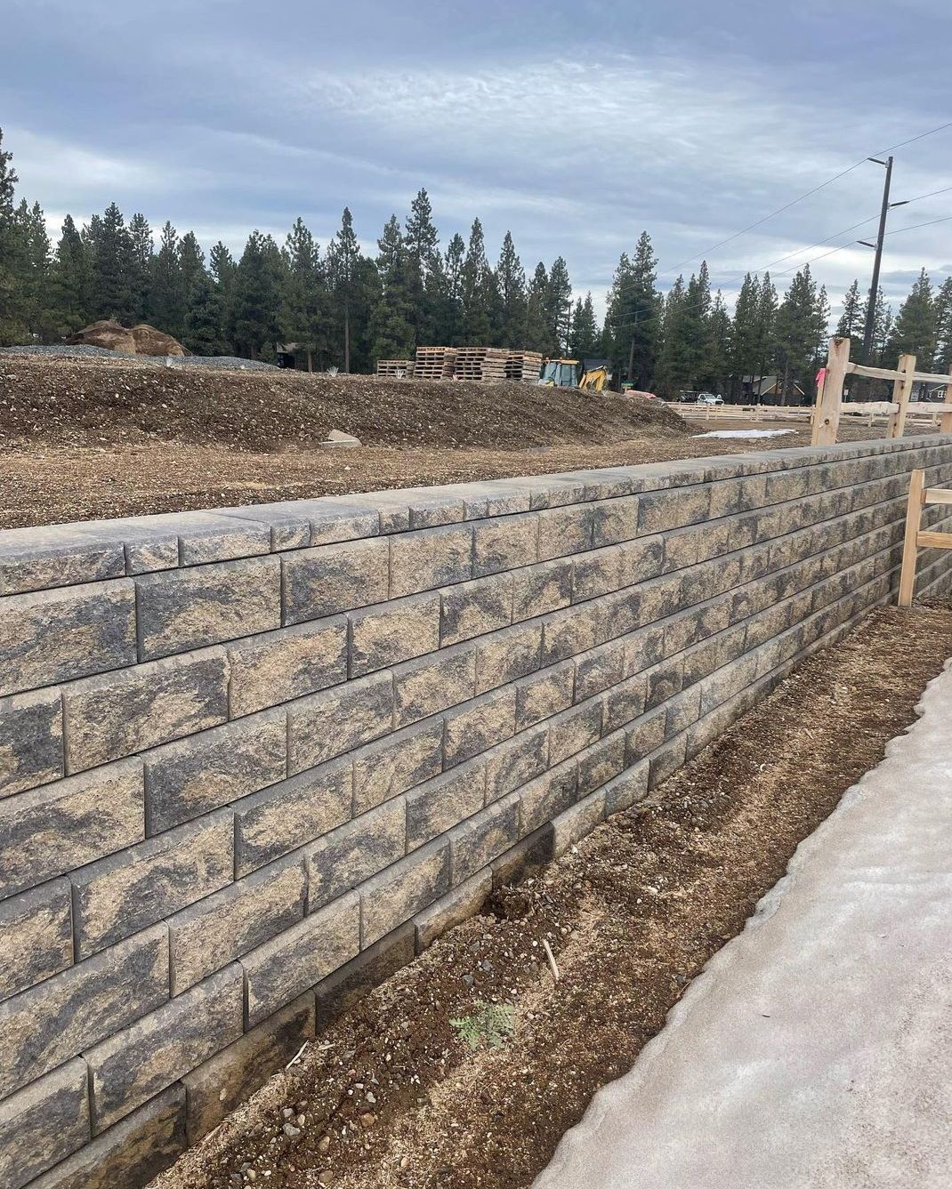 A large brick wall is being built next to a sidewalk.